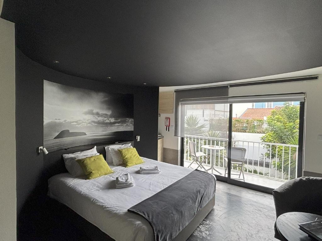 een slaapkamer met een groot bed en een groot raam bij LUZZ me - Casa de Angra in Angra do Heroísmo