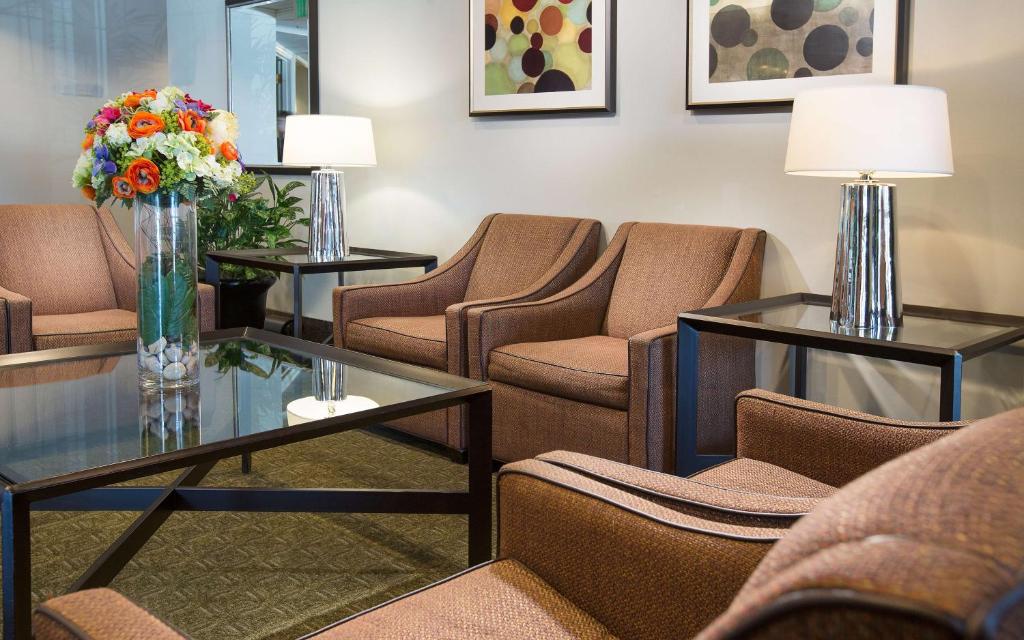 a waiting room with chairs and a table with flowers at Coast Gateway Hotel in SeaTac
