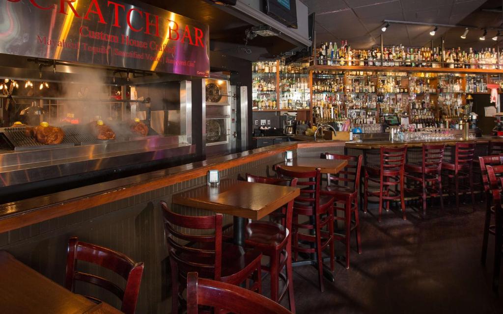 a bar with wooden tables and chairs and a lot of alcohol at Coast Gateway Hotel in SeaTac