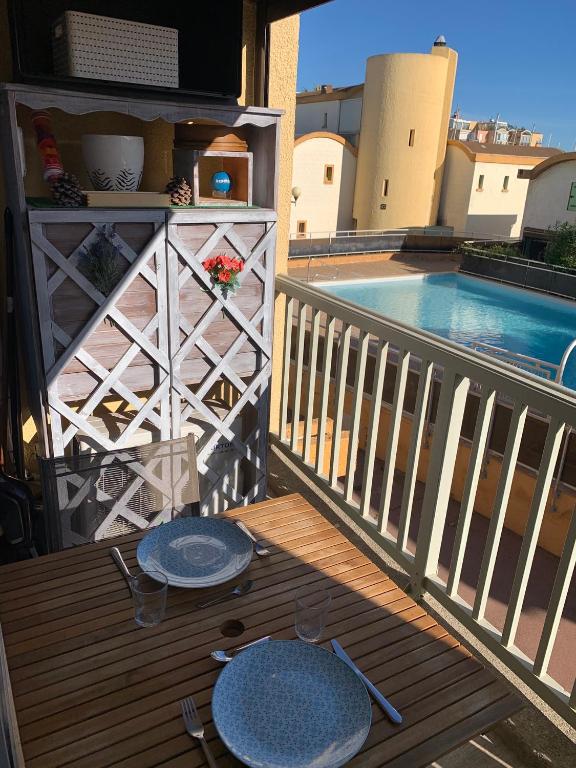 - un balcon avec une table et une piscine dans l'établissement Fleur Australe, à Gruissan