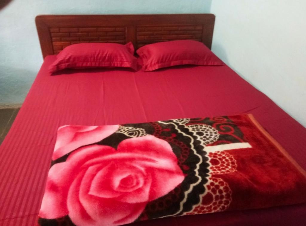 ein Bett mit einer roten Tagesdecke und einer rosa Rose darauf in der Unterkunft Sea Bird Holiday Home Behind Revdanda High school in Alībāg