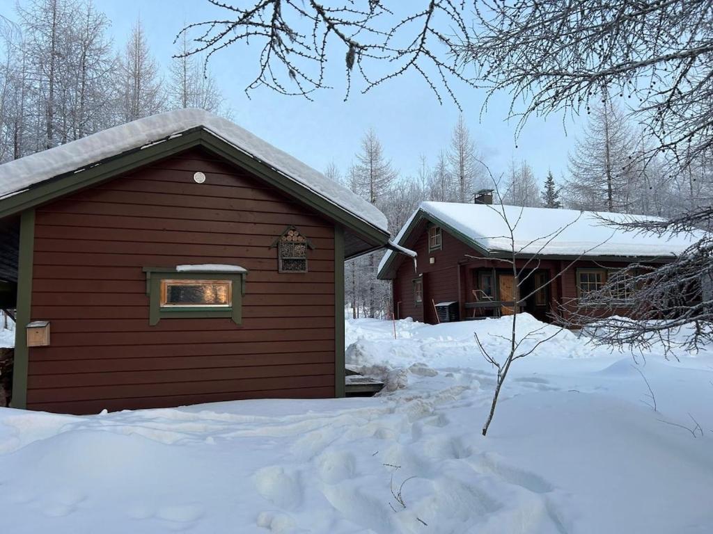 a building with snow on the ground next to a house at Forest and Lake Chalet in Pallas-Yllastunturi, Levi in Kittilä