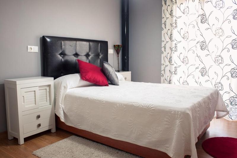 Un dormitorio con una cama con una almohada roja. en La Casa De Luarca, en Luarca