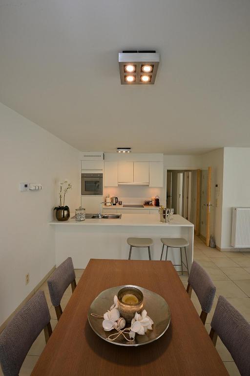 a kitchen and dining room with a wooden table and chairs at Residentie Rivella in Koksijde