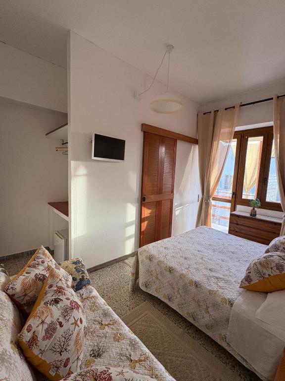 una camera da letto con due letti e una TV a parete di Vittorina's Home a Sorso