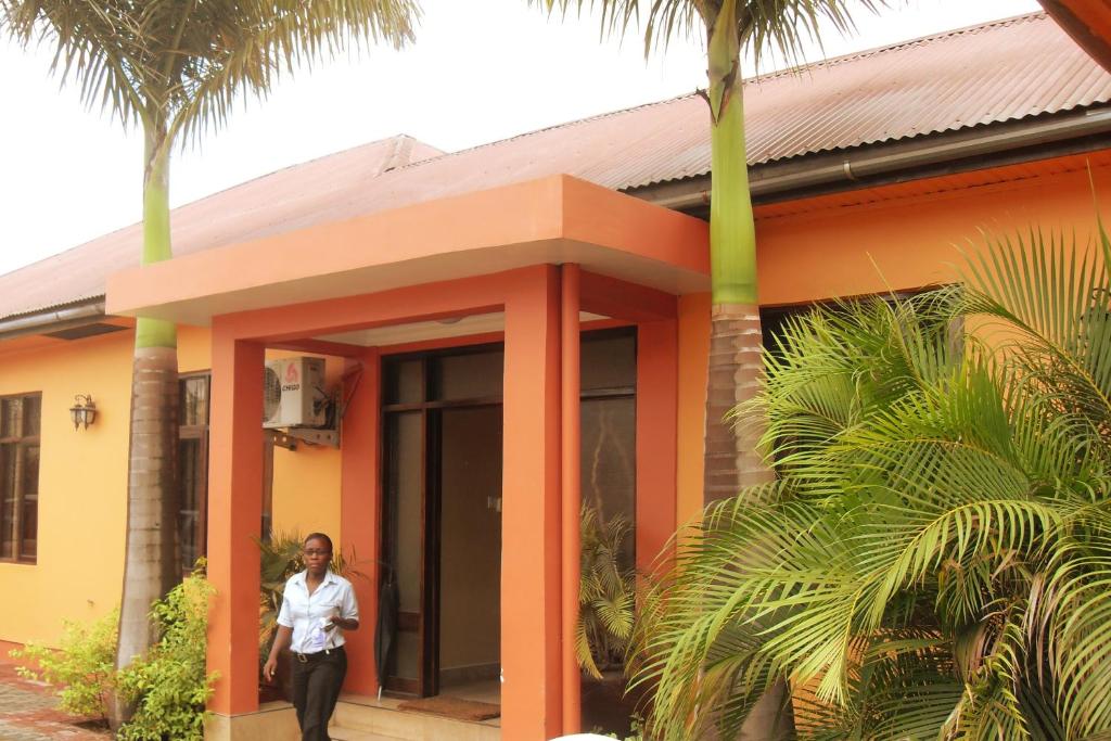 a woman standing outside of a house with palm trees at Transit Motel Ukonga in Dar es Salaam