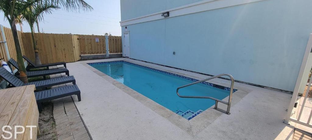 una pequeña piscina con 2 bancos junto a un edificio en Villas de Laguna 3, en South Padre Island