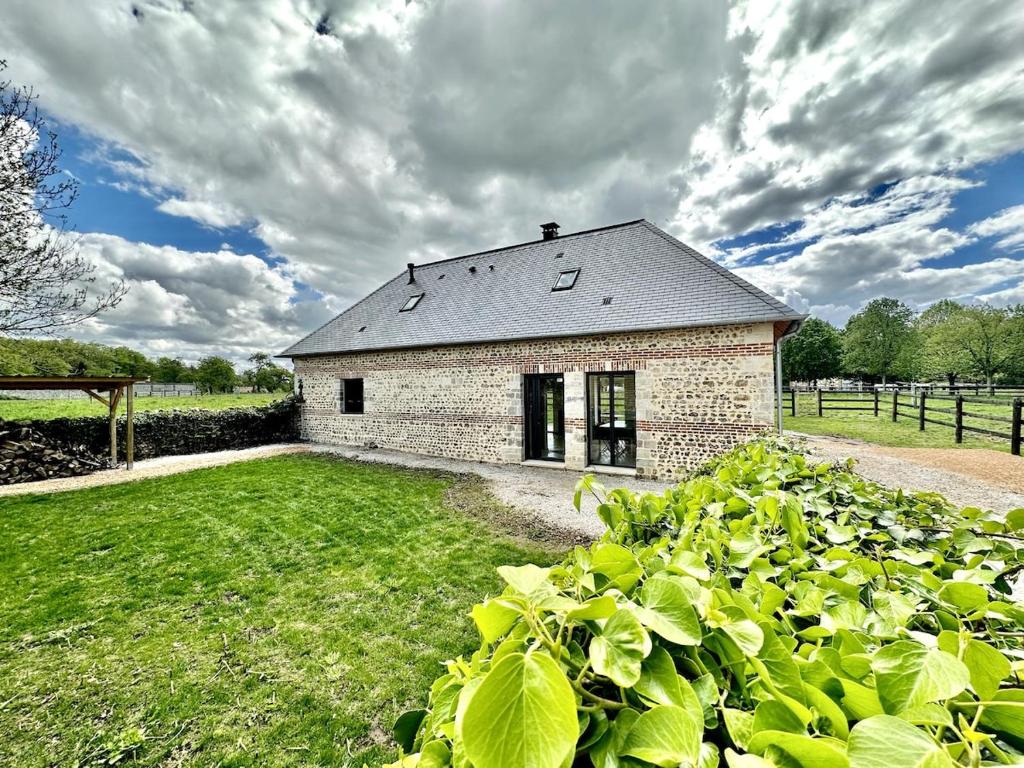 un petit bâtiment en briques dans un champ de plantes vertes dans l'établissement Gite de caractère entièrement restauré, à Saint-Pierre-du-Val