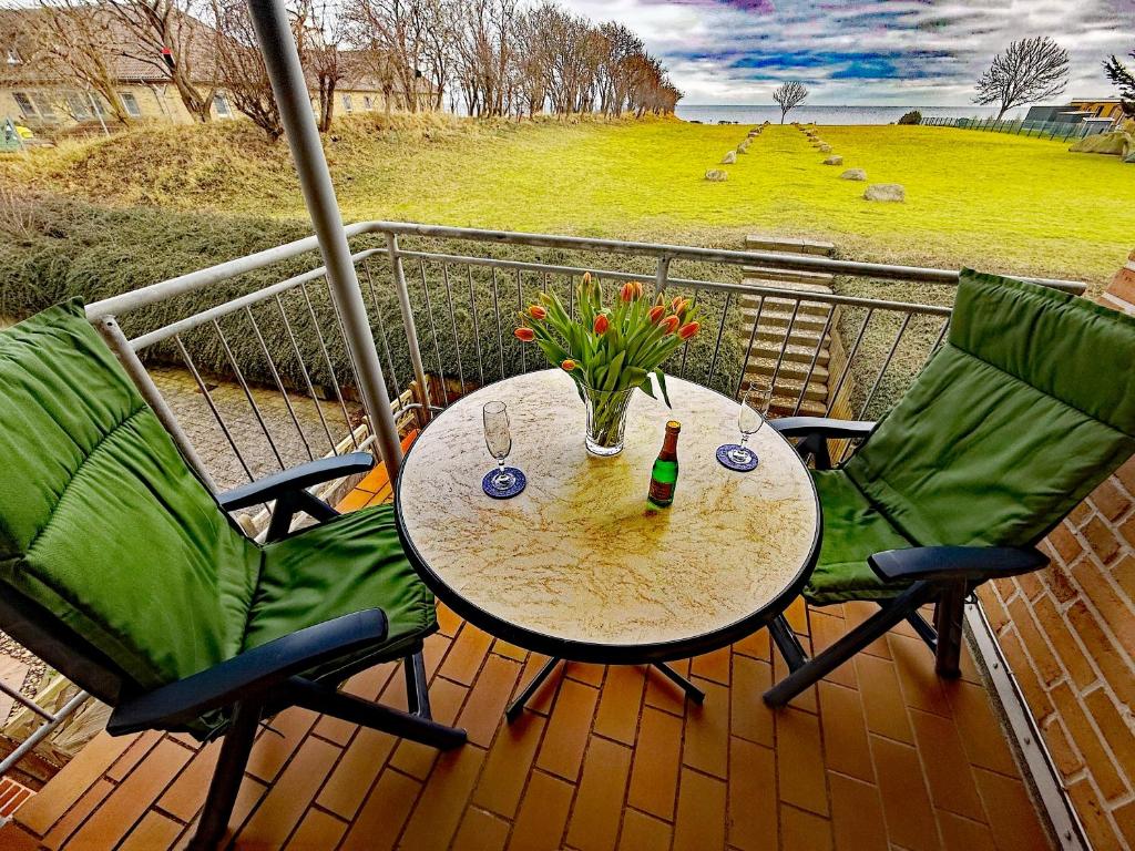 a table and two chairs on a balcony with a table and flowers at Bei den Leuchttürmen in Fehmarn