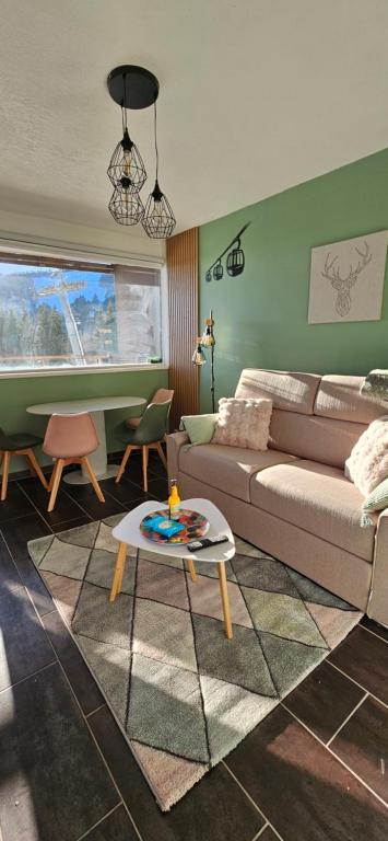 ein Wohnzimmer mit Sofa und Tisch in der Unterkunft LA PETITE LUGE studio sur les pistes centre station Super-Besse in Besse-et-Saint-Anastaise
