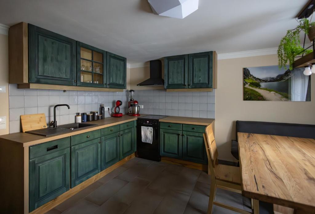 a kitchen with green cabinets and a wooden table at Heimathaus Hettegger neue gemütliche Ferienwohnung in Grossarl