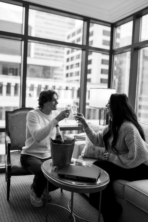 a man and woman sitting on a couch drinking wine at Hotel Le Soleil by Executive Hotels in Vancouver