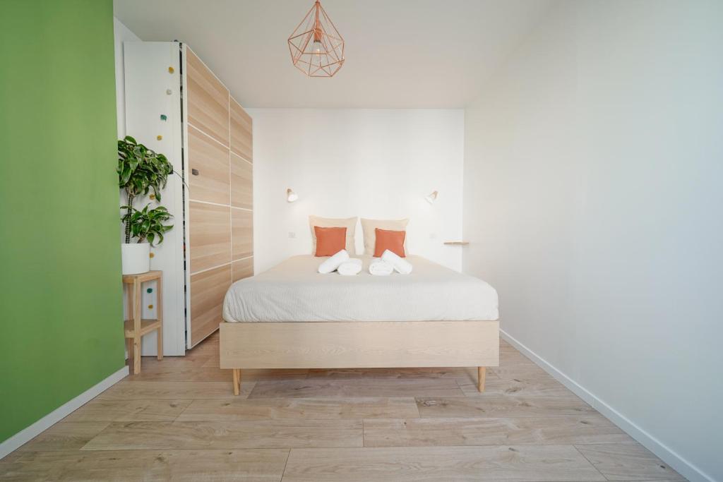 une chambre avec un lit avec des draps blancs et des oreillers orange dans l'établissement Ravissant cocon moderne - proche Stade de France, à Saint-Denis