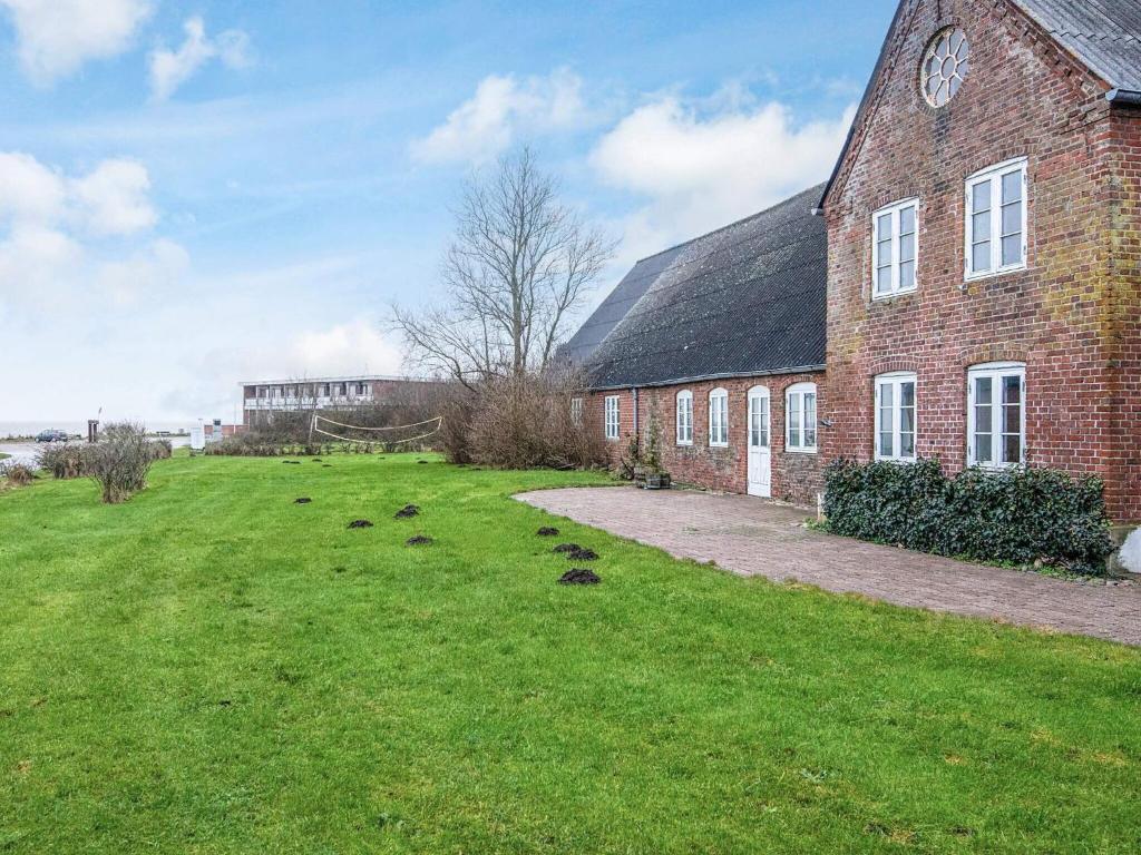 a large brick building with a grass field next to it at 4 star holiday home in Højer in Højer