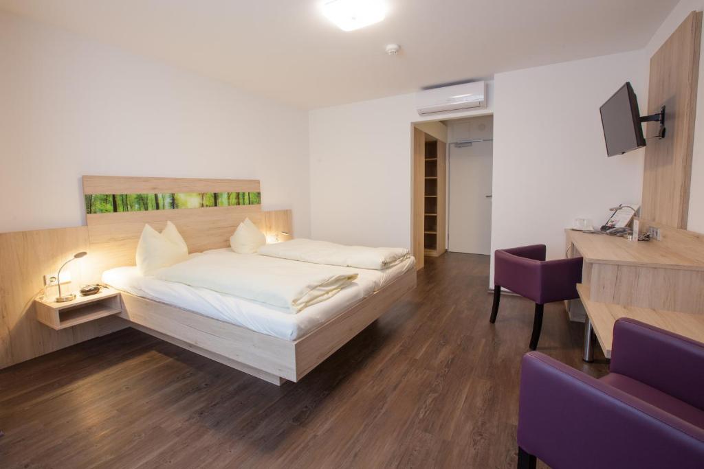 a bedroom with a large bed and a desk at Hotel zur Pfalz in Kandel