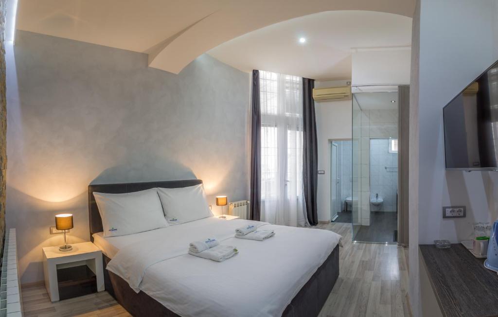 a bedroom with a large white bed and a bathroom at Central Park Residence in Belgrade