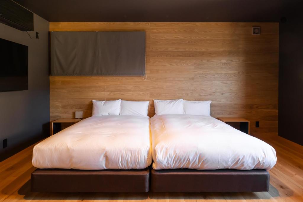 a bed with white sheets and pillows in a room at Kawaguchiko Country Cottage Ban in Fujikawaguchiko