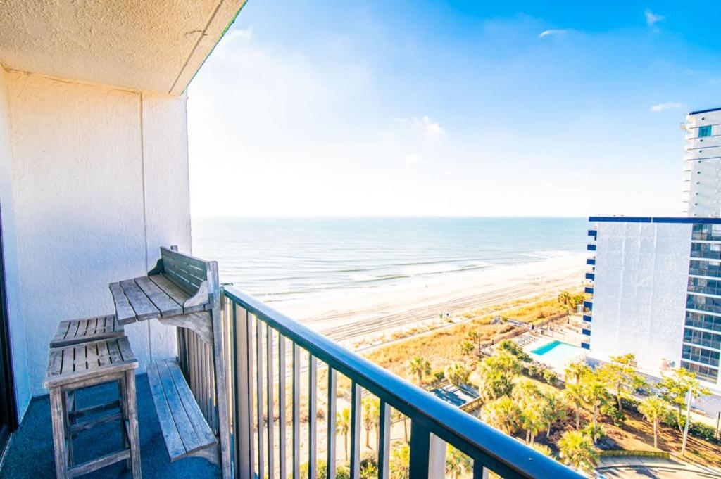 a balcony with a bench overlooking the beach at Oceanfront Pet Friendly Modern Suite in Myrtle Beach