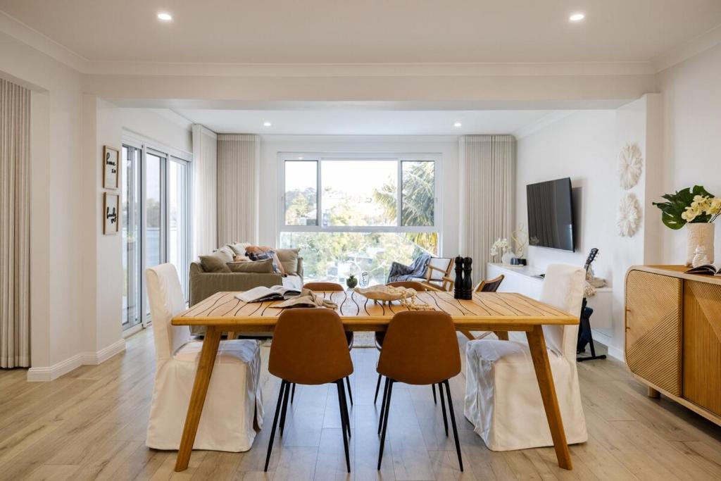 a dining room and living room with a table and chairs at Luxurious Waterfront Retreat in Oatley in Oatley