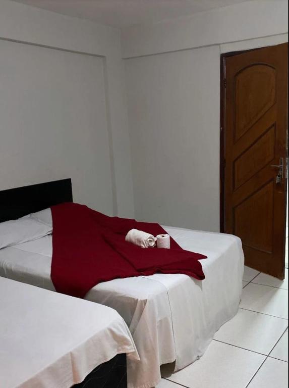 a bedroom with a bed with a red blanket on it at hotel conveniencia sul in Brasília