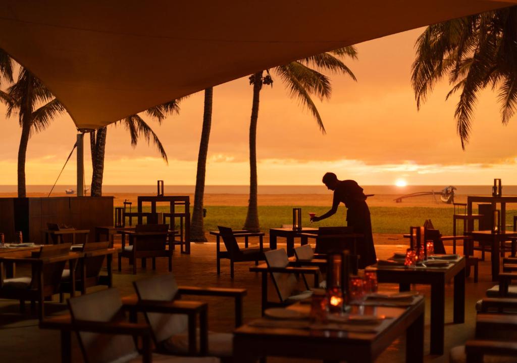 a man standing at a table in front of a restaurant at Jetwing Beach in Negombo