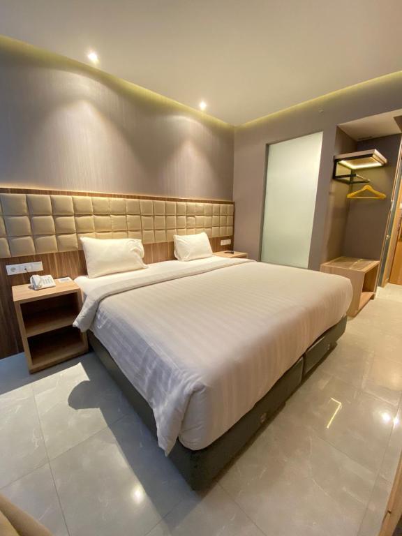 a bedroom with a large white bed in a room at OPA Hotel Palembang in Sukarami