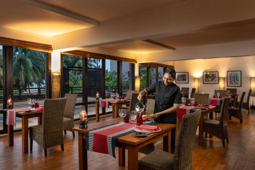 a man standing at a table in a restaurant at Jetwing Beach in Negombo