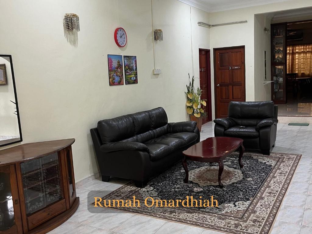 a living room with a leather couch and a table at Rumah Omardhiah in Kuala Terengganu