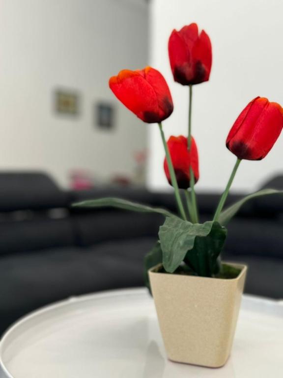 a vase filled with red flowers on a table at Yipstay Gopeng HomeTown in Gopeng