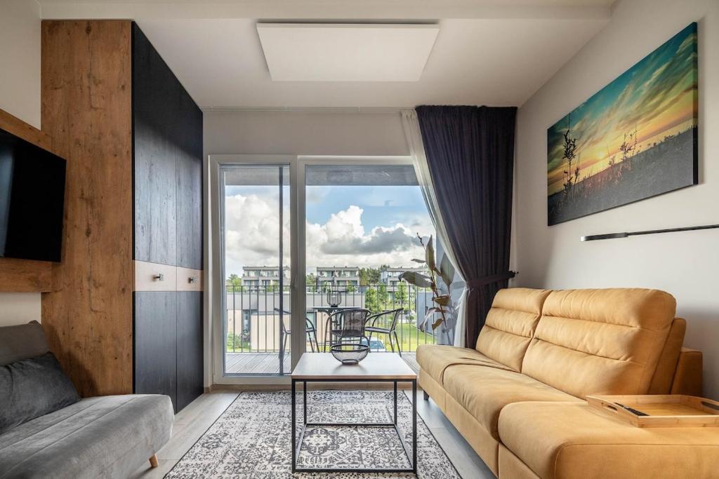 a living room with a couch and a large window at Cozy Palanga Apartment in Palanga