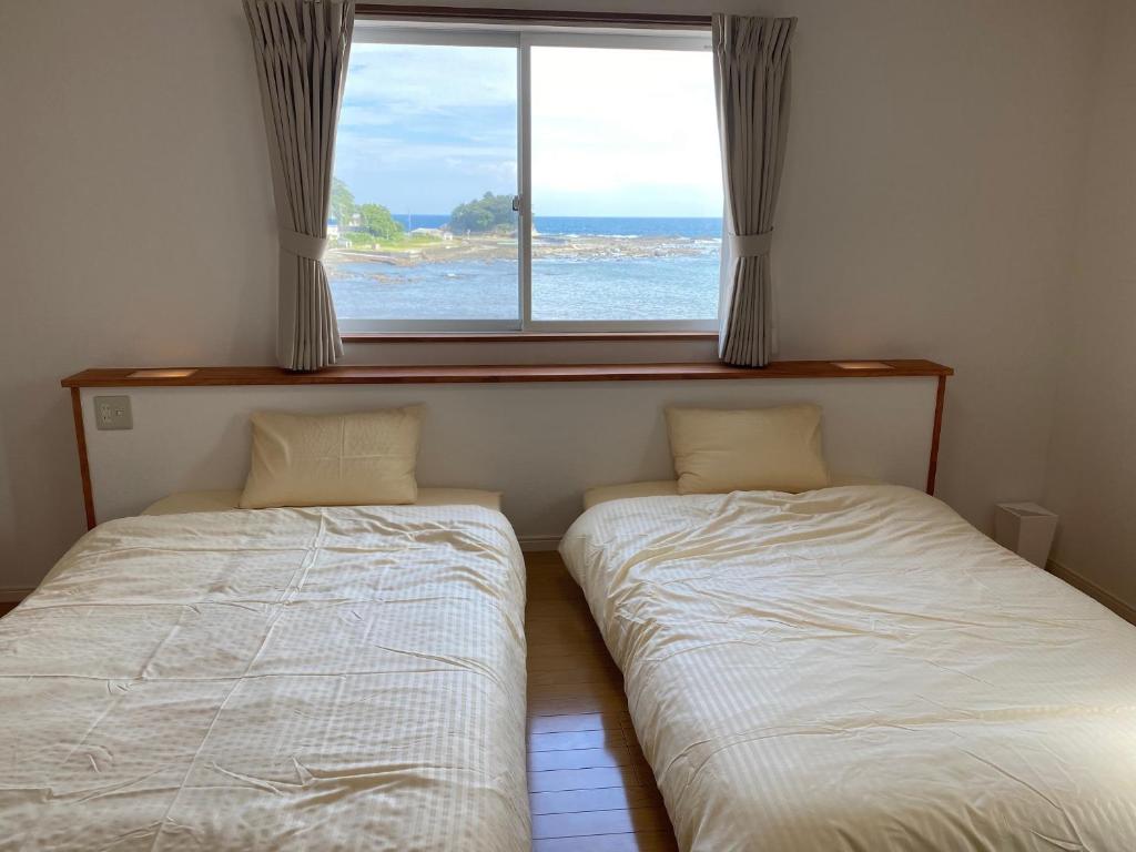 zwei Betten in einem Zimmer mit Fenster in der Unterkunft KR base Villa IzuShirahama Resort - Vacation STAY 33296v in Shimoda