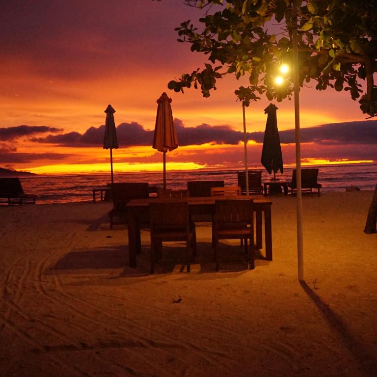 a table and umbrellas on a beach with a sunset at Mola2 Resort Gili Air in Gili Islands