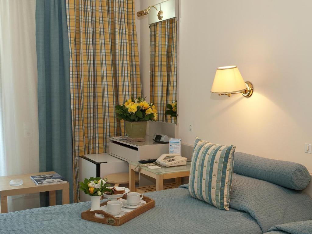 una sala de estar con una cama y una mesa con tazas. en The Park Hotel Piraeus, en Pireo