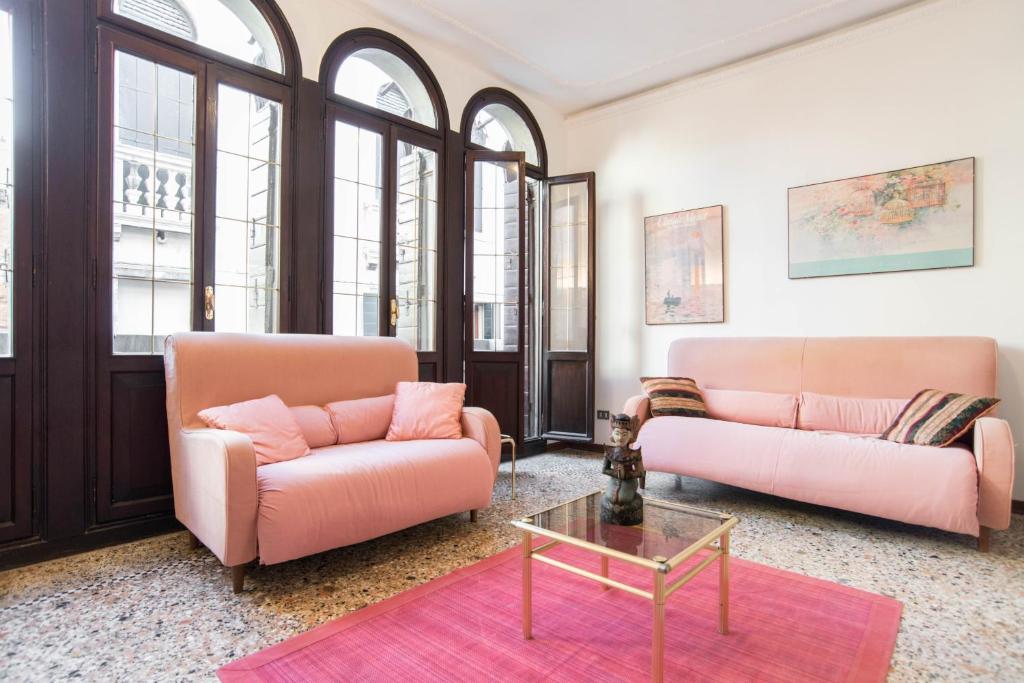 una sala de estar con 2 sofás rosas y una mesa. en Lustraferi Apartment, en Venecia