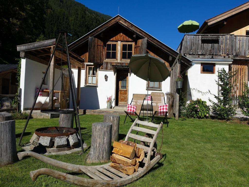 a house with a bench and an umbrella in the yard at Cabin in Stans near Kellerjoch Ski Area in Stans