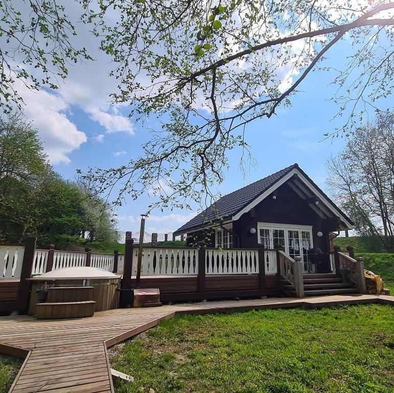 a house with a fence and a wooden deck at Sodyba Barracuda in Kupščiai