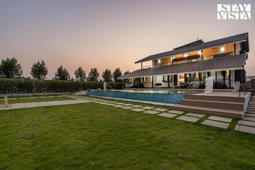 a villa with a swimming pool and a lawn at StayVista at Blisswood Cottage with Pool & Bar in Nashik