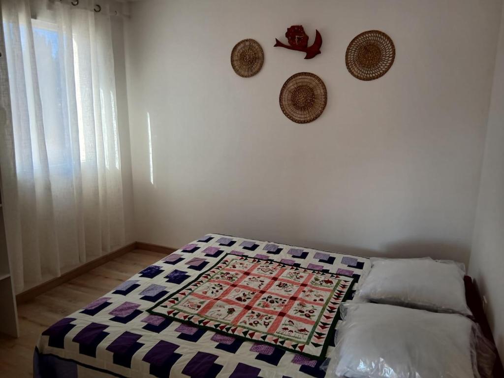 SabletMaison à Sablet的卧室内的一张床铺,墙上挂着帽子