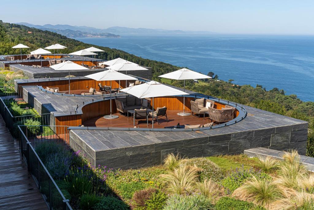 a restaurant with tables and umbrellas on top of a hill at Akelarre - Relais & Châteaux in Donostia-San Sebastián