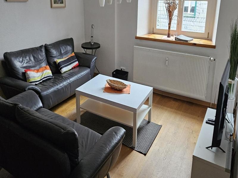 a living room with a black couch and a table at Zum alten Landrat in Monschau