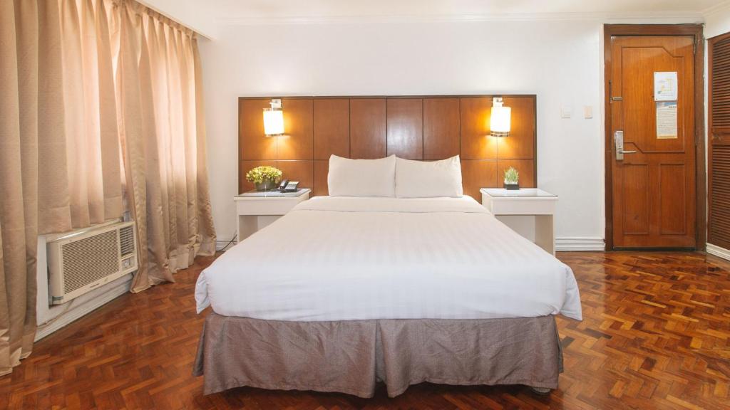 a bedroom with a large bed with white sheets at Comfy Inn Manila Kalaw by RedDoorz in Manila
