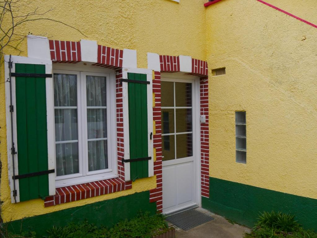 un bâtiment jaune avec des fenêtres vertes et une porte blanche dans l'établissement la maison jaune proche mer et marché avec wifi, à Pornichet