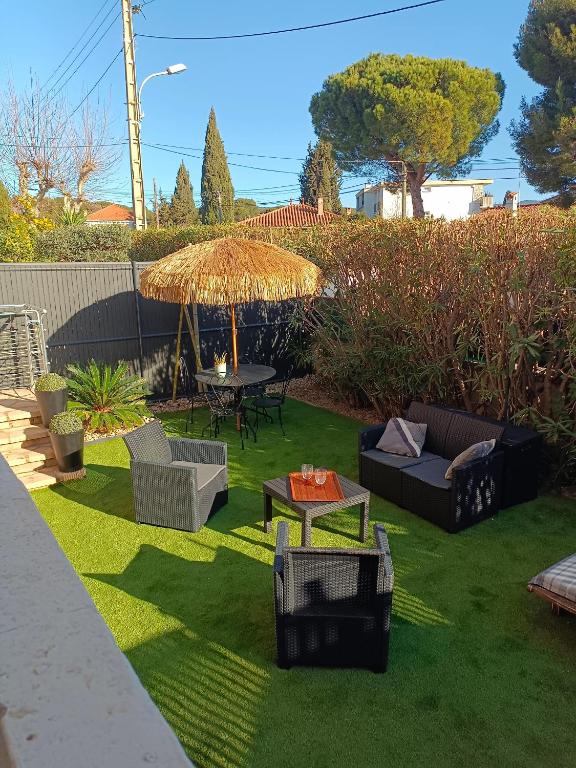 une cour avec une pelouse meublée et un parasol dans l'établissement le cytharis, à La Ciotat