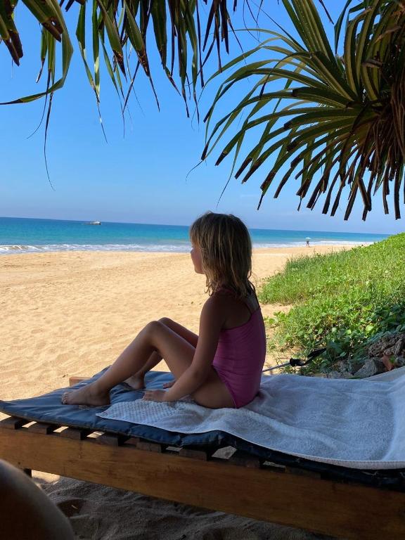 a woman sitting on a towel on the beach at Coastal Heaven in Bentota