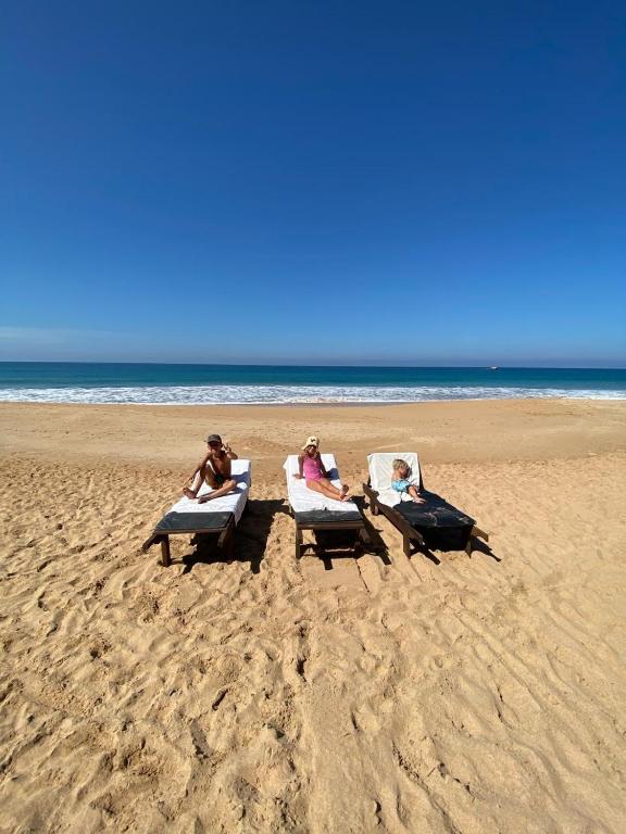 three people sitting in lounge chairs on the beach at Coastal Heaven in Bentota