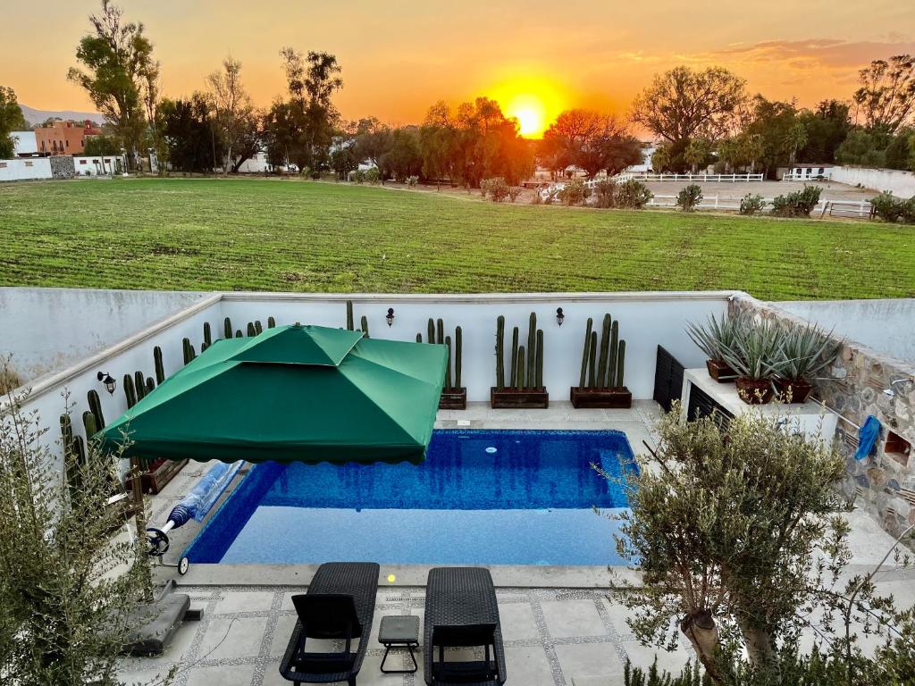 a pool with a green umbrella and chairs and a sunset at Casa Frida con Piscina Privada Caliente, Aire Acondicionado, Billar, Parrilla & FirePit in San Miguel de Allende