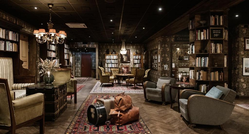 a library with chairs and bookshelves with a suitcase on the floor at Hotell Gästis in Varberg