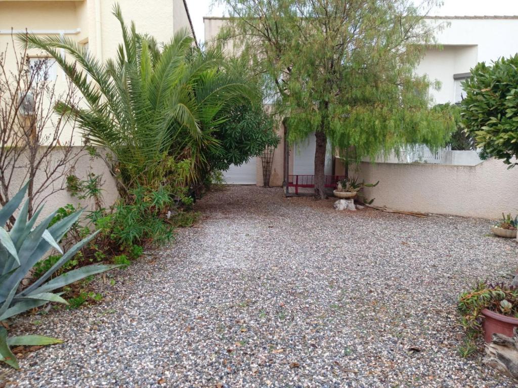 une cour d'une maison avec des arbres et des plantes dans l'établissement Agréable maison de vacances, à Port-la-Nouvelle