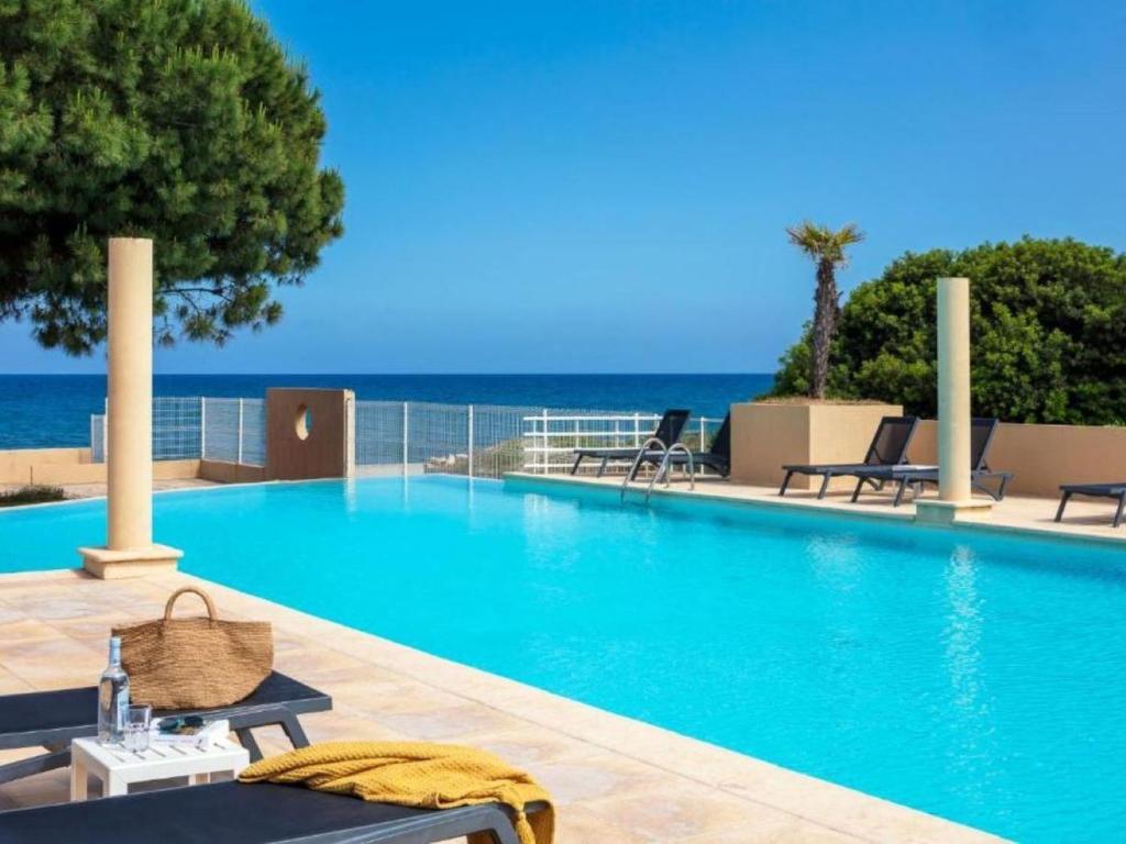 une piscine avec des chaises et l'océan en arrière-plan dans l'établissement Apartment MB6 sans vue mer by Interhome, à Moriani-Plage