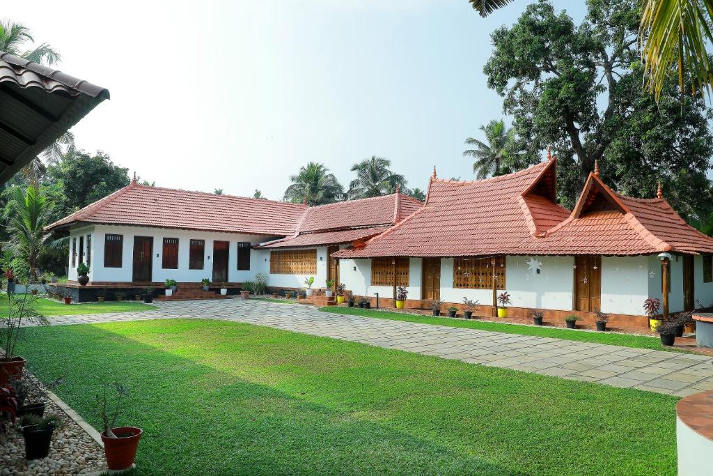a building with red roofing on top of a yard at Mulanthanam resorts and Home stay in Champakulam